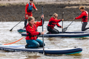 A group of young people learning how to paddleboard in Plymouth Sound