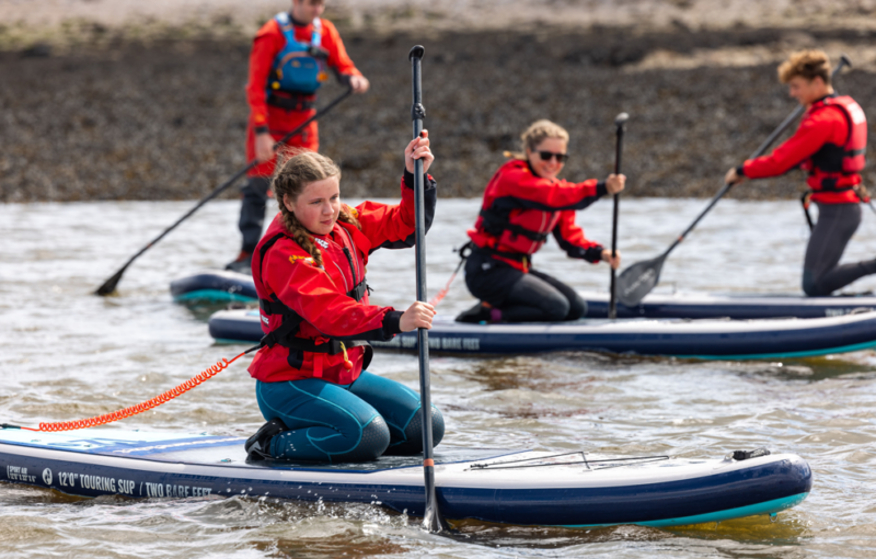 A group of young people learning how to paddleboard in Plymouth Sound