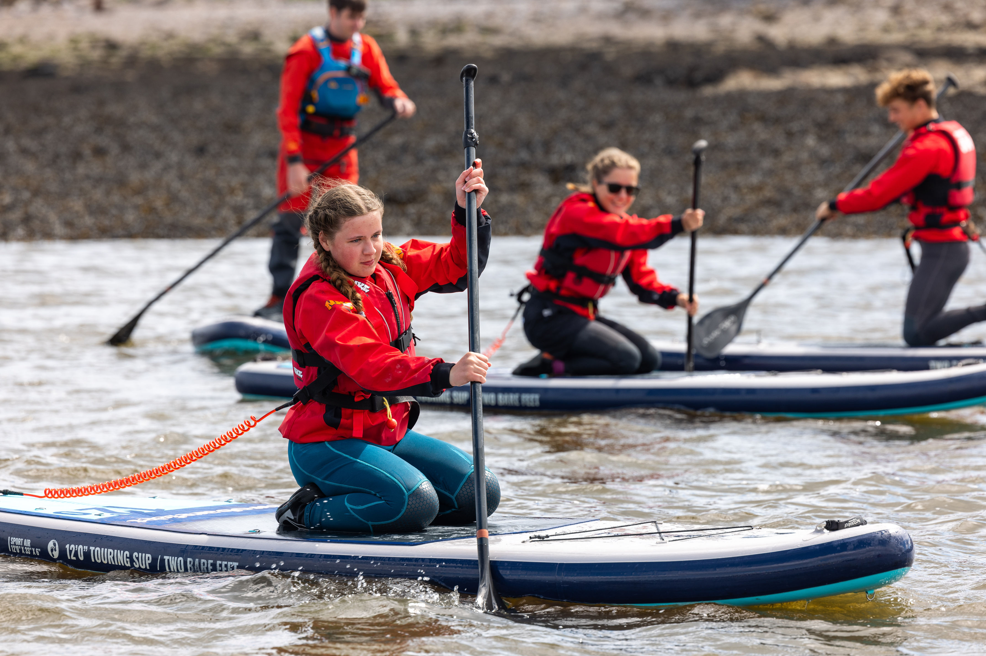 A group of young people learning how to paddleboard in Plymouth Sound