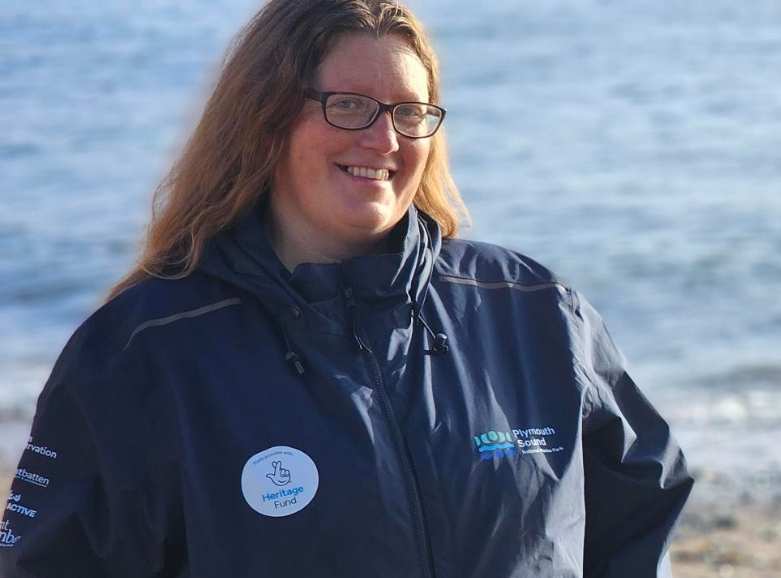Coastal Ranger Jes with long, light brown hair and glasses, stood on Cawsand Beach