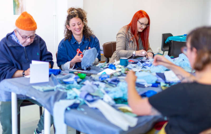 People about a table doing arts and crafts as a part of Megan Roberts 'And Breathe' project as a part of the Sea for Yourself programme.
