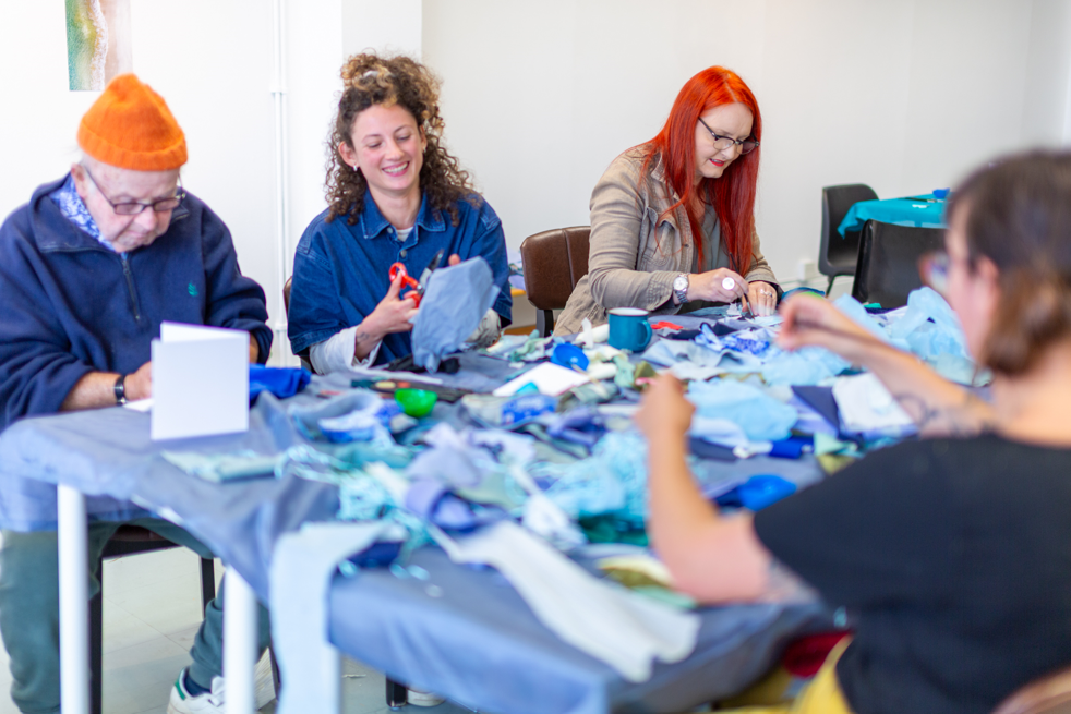 People about a table doing arts and crafts as a part of Megan Roberts 'And Breathe' project as a part of the Sea for Yourself programme.