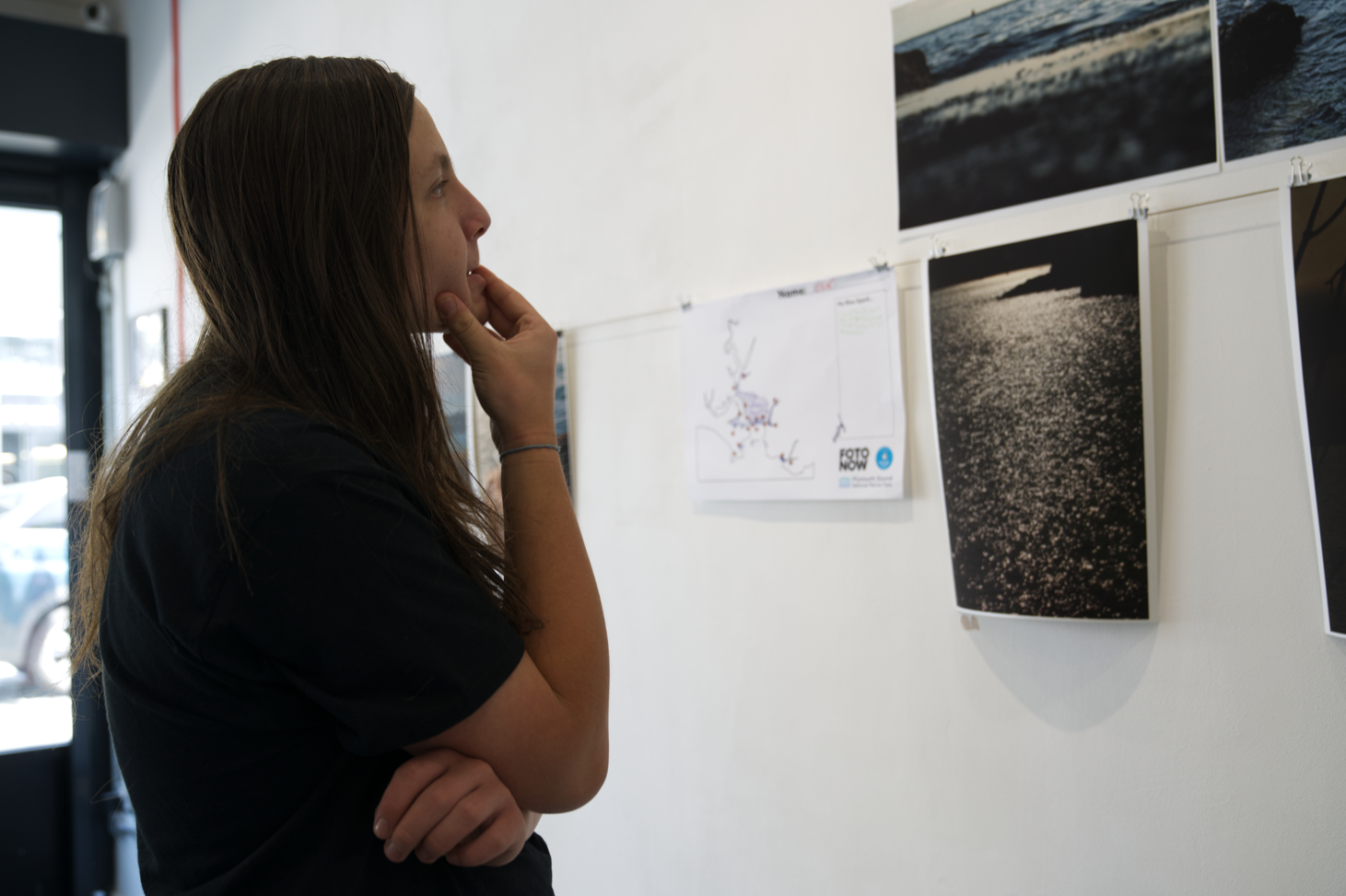 Blue Sparks - Fotonow CIC - Young person viewing printed photos of the sea on a gallery wall