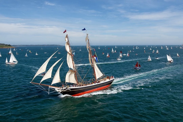 Historic ship with big white sails, cutting through the waves of the sea