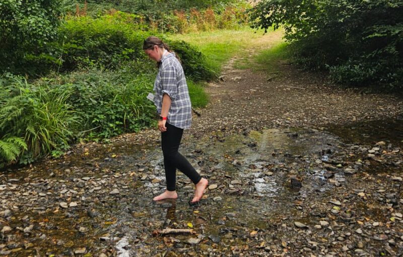 A woman walking through a stream in Cann Woods during a Southway to the Sea session.